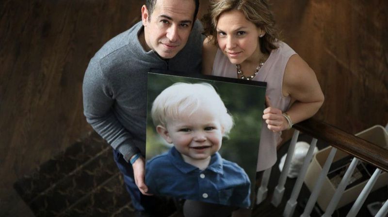 Greiving parents holding photo of dead son