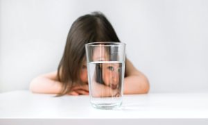 Child Looking Through Glass Of Water