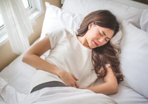 Girl with Stomach Pain In Bed